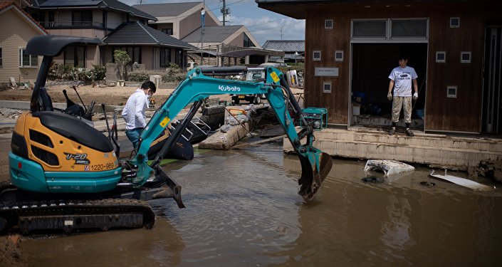 People remove water and mud with an excavator in a flood hit area in Mabi, Okayama prefecture