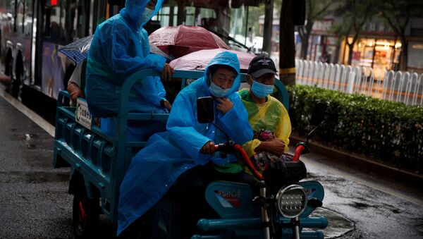 Рабочие в защитных масках и дождевиках на электрическом трицикле в дождливый день после вспышки коронавирусной болезни (COVID-19) в Пекине - 俄羅斯衛星通訊社