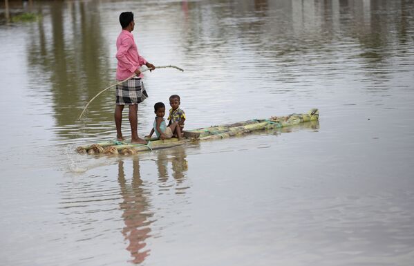 Индиец с детьми плывет на плоту во время наводнения в штате Ассам - 俄羅斯衛星通訊社