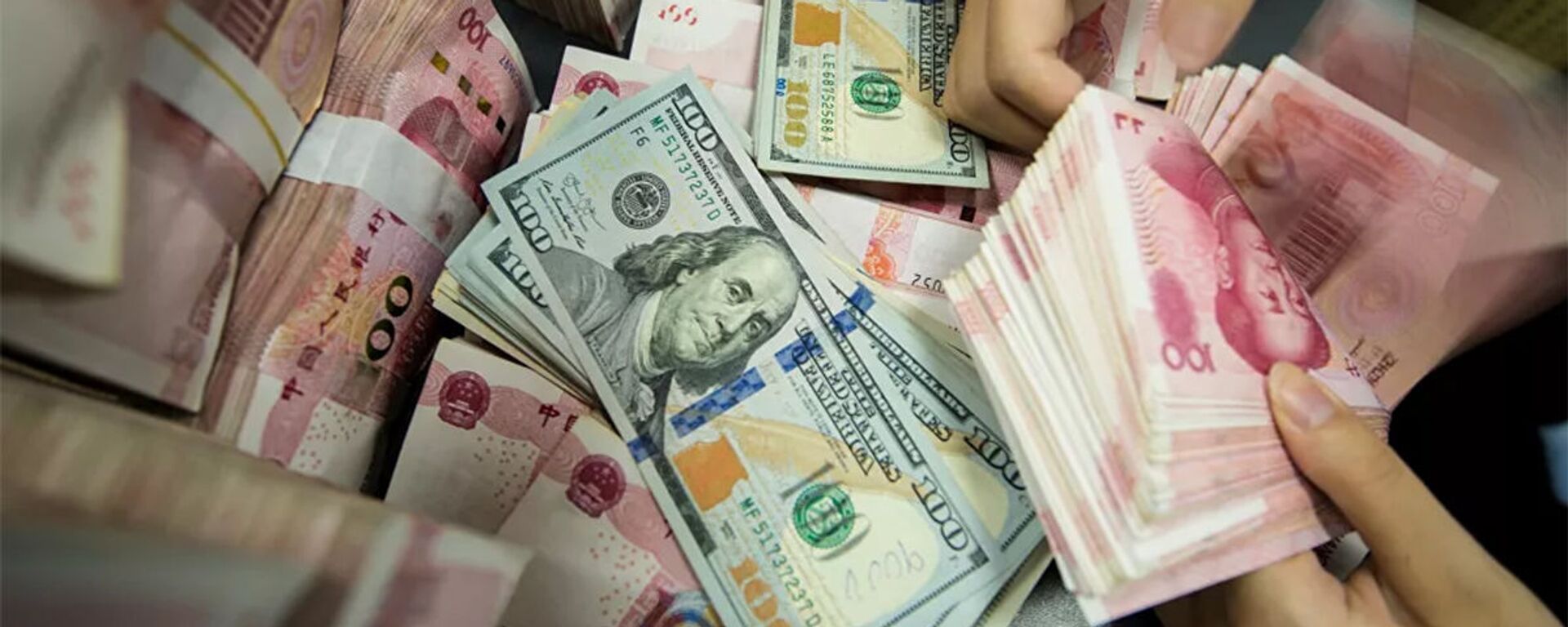 A Chinese bank employee counts 100-yuan notes and US dollar bills at a bank counter in Nantong in China's eastern Jiangsu province  - 俄羅斯衛星通訊社, 1920, 04.06.2021