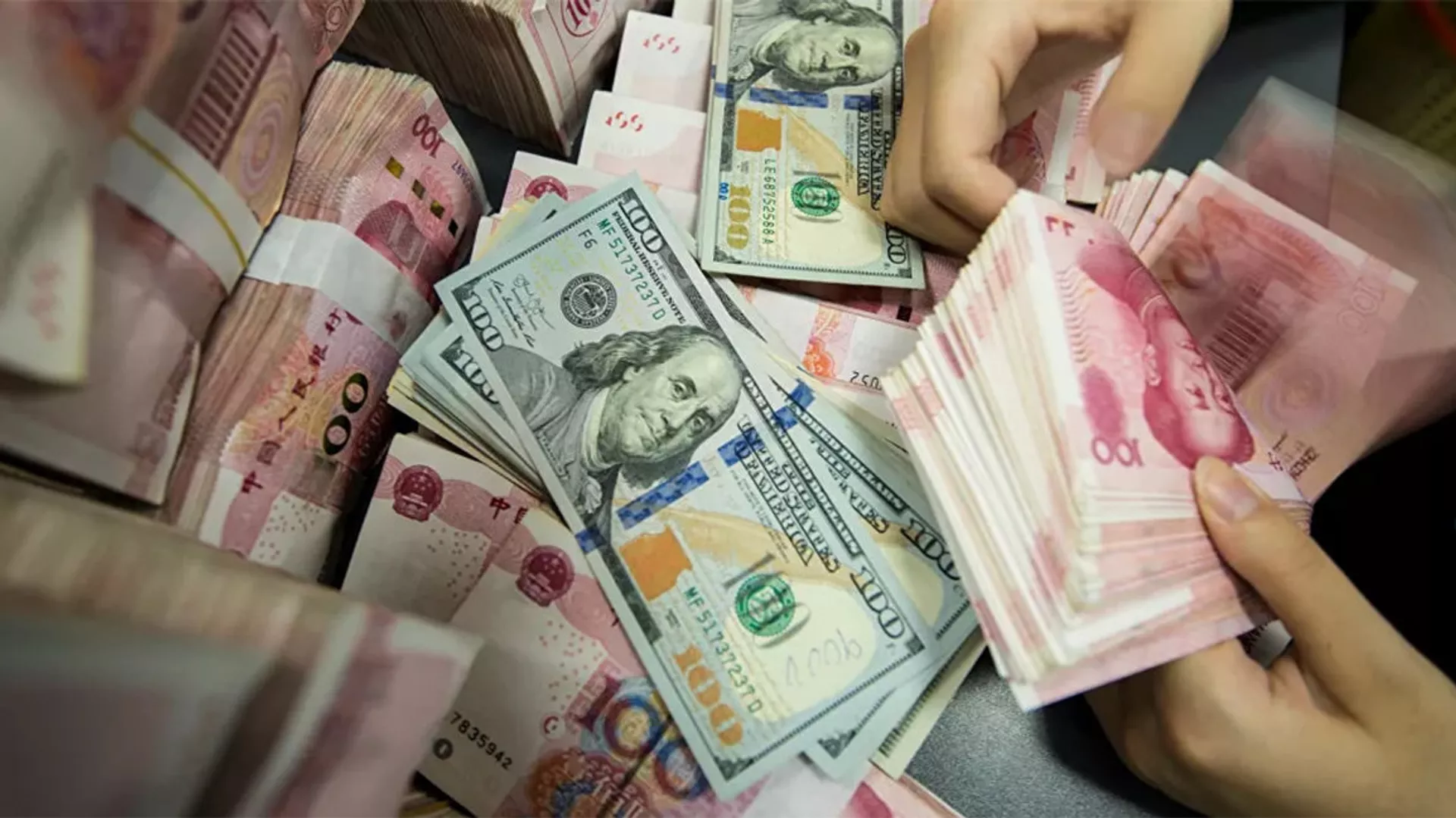 A Chinese bank employee counts 100-yuan notes and US dollar bills at a bank counter in Nantong in China's eastern Jiangsu province  - 俄罗斯卫星通讯社, 1920, 04.06.2021