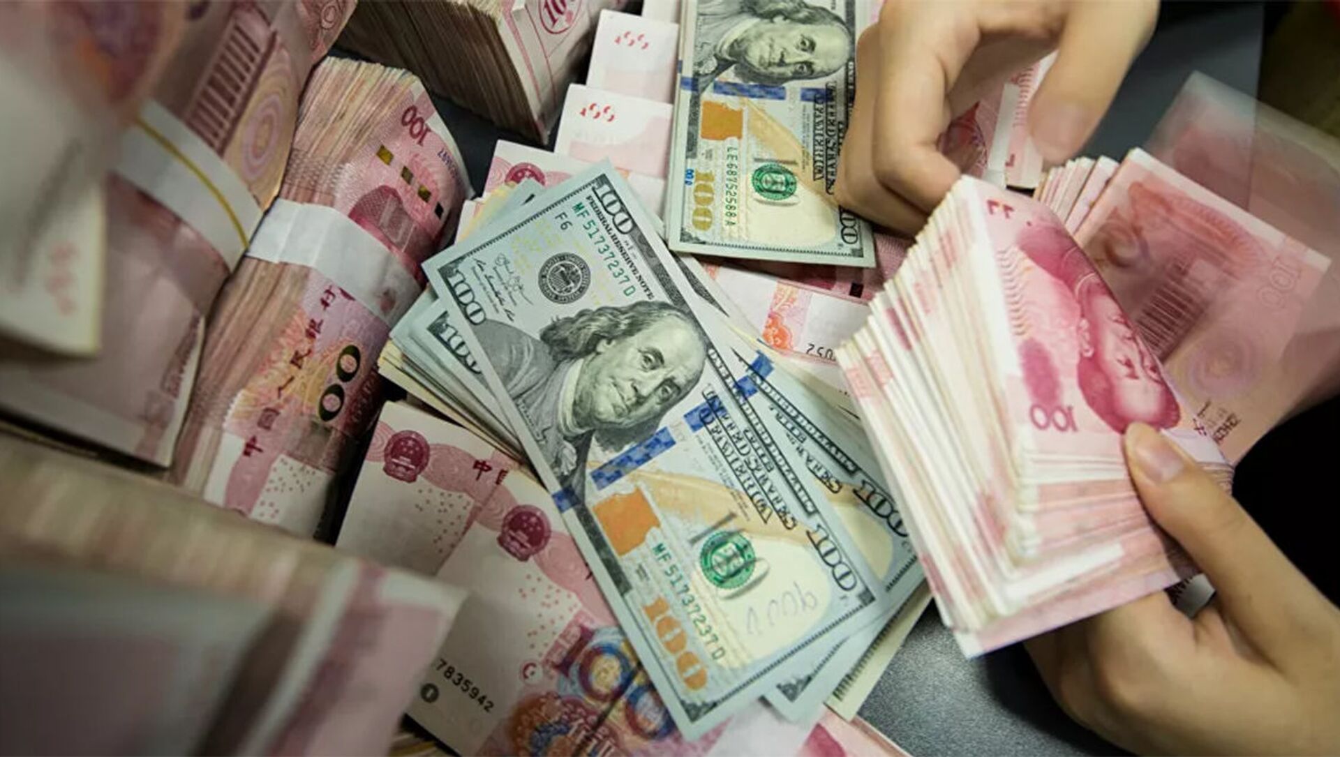 A Chinese bank employee counts 100-yuan notes and US dollar bills at a bank counter in Nantong in China's eastern Jiangsu province  - 俄羅斯衛星通訊社, 1920, 20.10.2021