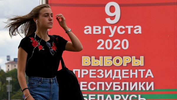 Девушка на фоне информационного предвыборного плаката на одной из улиц Минска.  - 俄罗斯卫星通讯社
