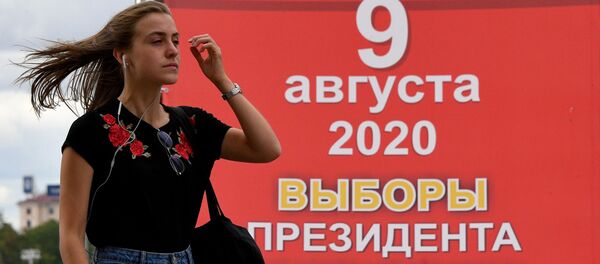 Девушка на фоне информационного предвыборного плаката на одной из улиц Минска. Девушка на фоне информационного предвыборного плаката на одной из улиц Минска. - 俄羅斯衛星通訊社
