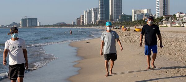 Люди, одетые в защитные маски, гуляют по пляжу My Khe в Дананге, Вьетнам - 俄罗斯卫星通讯社