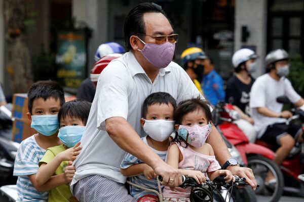 Мужчина с детьми на велосипеде, в защитных маска, на улицах Ханоя, Вьетнам - 俄罗斯卫星通讯社