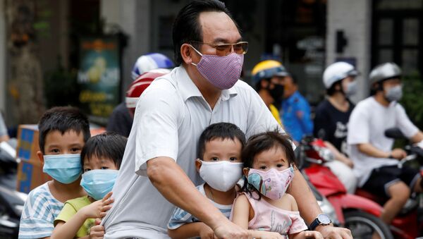 Мужчина с детьми на велосипеде, в защитных маска, на улицах Ханоя, Вьетнам - 俄羅斯衛星通訊社
