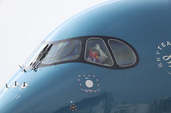 Пилот в защитном костюме держит флаги Вьетнама после посадки в аэропорту в Ханое, Вьетнам - 俄罗斯卫星通讯社