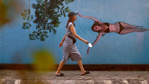 Девушка в защитной маске на фоне граффити с изображением девушки в купальнике в Джакарте, Индонезия - 俄罗斯卫星通讯社