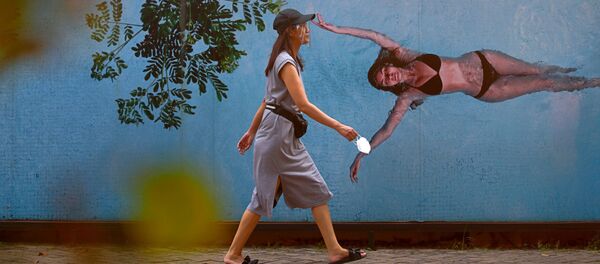 Девушка в защитной маске на фоне граффити с изображением девушки в купальнике в Джакарте, Индонезия - 俄罗斯卫星通讯社