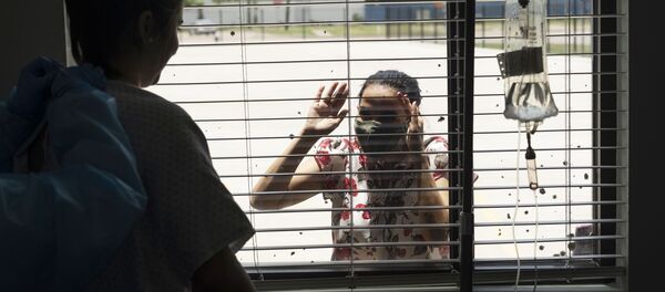 Пациентка общается через стекло с родственниками в госпитале United Memorial Medical Center в Хьюстоне, где проходят лечение больные с COVID-19.  - 俄罗斯卫星通讯社