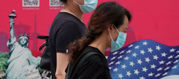 Женщины в защитных масках проходят мимо рекламного щита в Пекине Женщины в защитных масках проходят мимо рекламного щита в Пекине - 俄罗斯卫星通讯社