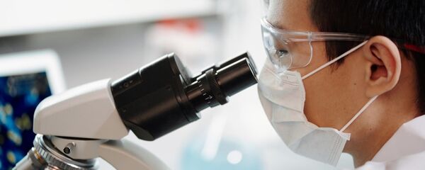 Азиатский мужчина смотрит в микроскоп - 俄罗斯卫星通讯社