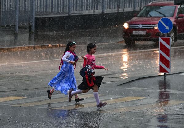 Девочки перебегают через дорогу во время сильного дождя в Москве - 俄罗斯卫星通讯社
