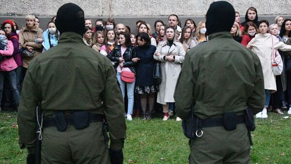 Люди в камуфляжной форме стоят напротив участников акции протеста в Минске - 俄罗斯卫星通讯社