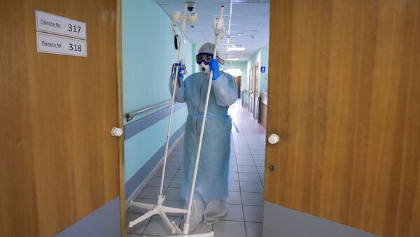 Медицинский работник несет штативы для капельниц в стационаре для больных с коронавирусной инфекцией - 俄罗斯卫星通讯社