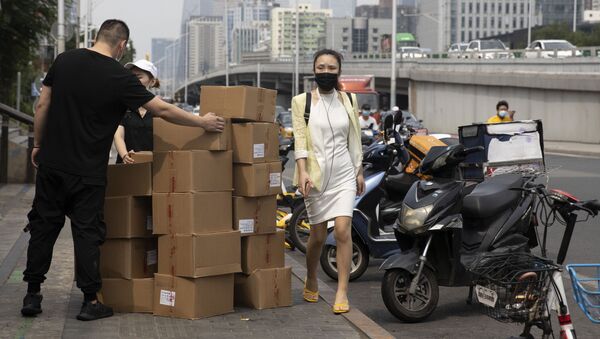 Девушка в маске на фоне мужчин, разгружающих коробки - 俄罗斯卫星通讯社