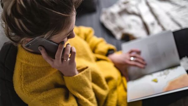 Девушка разговаривает по телефону и читает журнал - 俄罗斯卫星通讯社