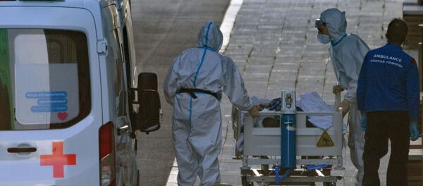  Медицинские работники везут на каталке пациентку, доставленную бригадой скорой медицинской помощи, в здание карантинного центра в Коммунарке.  - 俄罗斯卫星通讯社