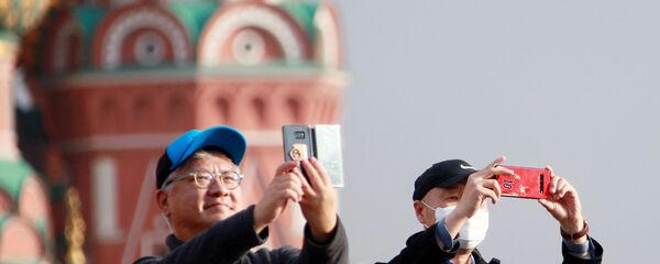 Мужчины в медицинских масках фотографируются около Собора Василия Блаженного на Красной площади в Москве. - 俄罗斯卫星通讯社