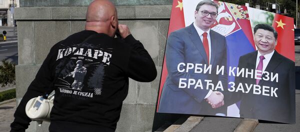 Мужчина на фоне плаката с изображением глав Сербии и Китая - 俄罗斯卫星通讯社