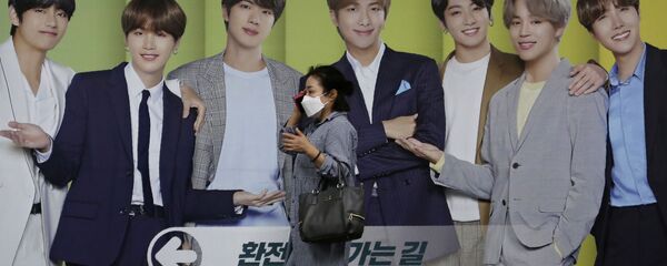 Девушка разговаривает по телефону на фоне плаката с K-pop группой BTS Девушка разговаривает по телефону на фоне плаката с K-pop группой BTS - 俄罗斯卫星通讯社