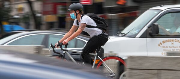 Велосипедист в защитной маске едет по улице в Нью-Йорке.  - 俄羅斯衛星通訊社