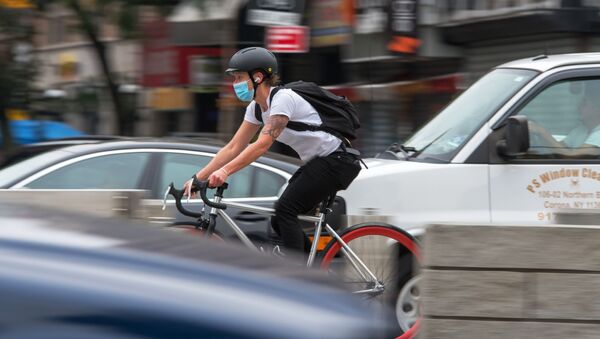 Велосипедист в защитной маске едет по улице в Нью-Йорке.  - 俄羅斯衛星通訊社