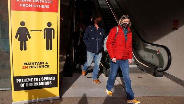 Люди в защитных масках проходят мимо знака социального дистанцирования в Ковентри, Великобритания - 俄罗斯卫星通讯社