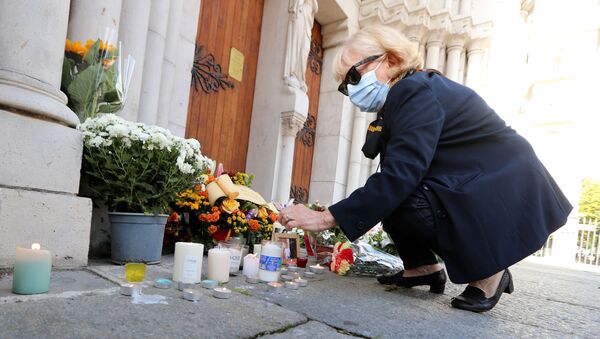 Женщина зажигает свечу у собора Нотр-Дам в Ницце, где произошло нападение на людей - 俄羅斯衛星通訊社