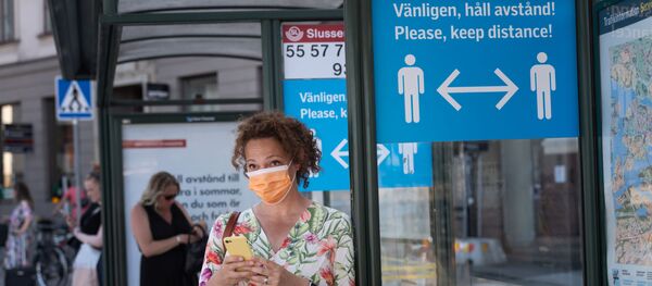Женщина в маске на автобусной остановке в Стокгольме - 俄罗斯卫星通讯社
