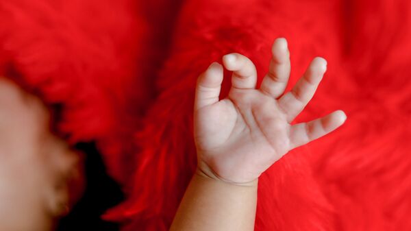Рука младенца на красном фоне - 俄羅斯衛星通訊社