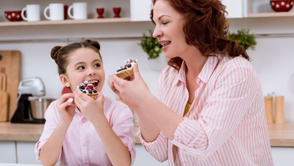 Женщина с девочкой едят пирожные на кухне - 俄羅斯衛星通訊社