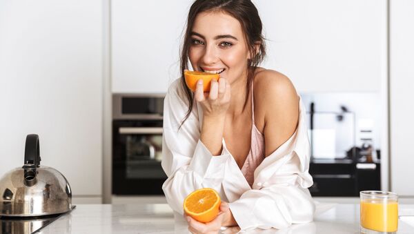 Девушка ест апельсин на кухне - 俄罗斯卫星通讯社