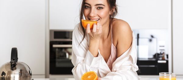 Девушка ест апельсин на кухне - 俄羅斯衛星通訊社
