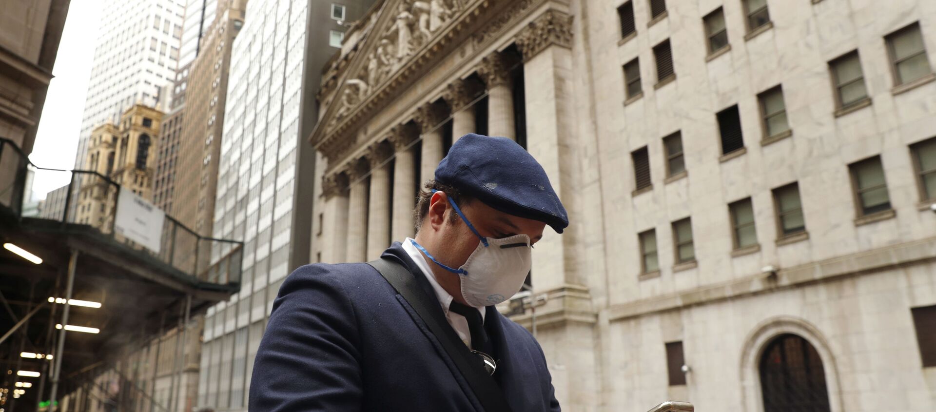 A man wears a protective mask as he walks past the New York Stock Exchange on the corner of Wall and Broad streets during the coronavirus outbreak in New York City, New York, U.S., March 13, 2020 - 俄罗斯卫星通讯社, 1920, 17.09.2021