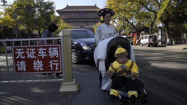Женщина в традиционном китайском костюме с ребенком, одетым как император, возле Запретного города в Пекине. - 俄羅斯衛星通訊社