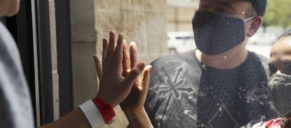 Пациентка общается через стекло с родственниками в госпитале United Memorial Medical Center в Хьюстоне, где проходят лечение больные с COVID-19.  - 俄罗斯卫星通讯社