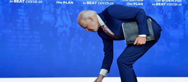 Кандидат в президенты США Джо Байден наклоняется за упавшей медицинской маской - 俄罗斯卫星通讯社