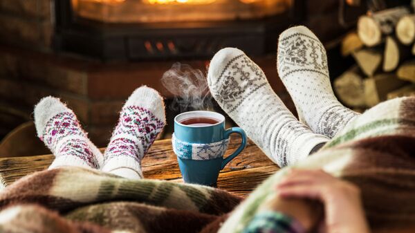 Люди в теплых носках отдыхают с чашкой чая у камина - 俄罗斯卫星通讯社