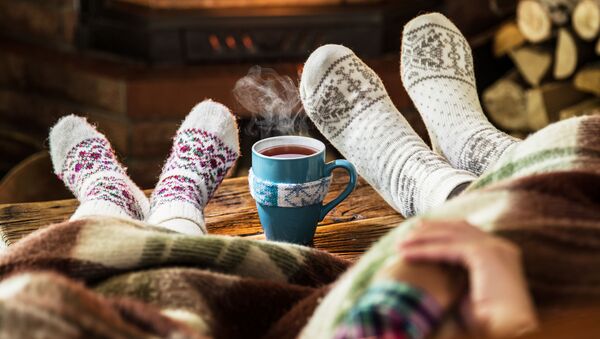 Люди в теплых носках отдыхают с чашкой чая у камина - 俄罗斯卫星通讯社