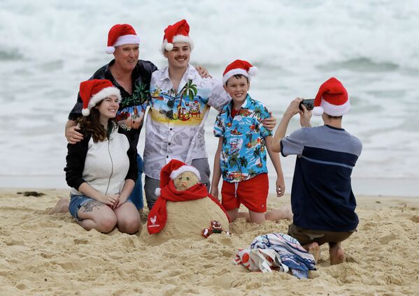Семья в рождественских колпаках фотографируется на пляже в Сиднее, Австралия  - 俄罗斯卫星通讯社