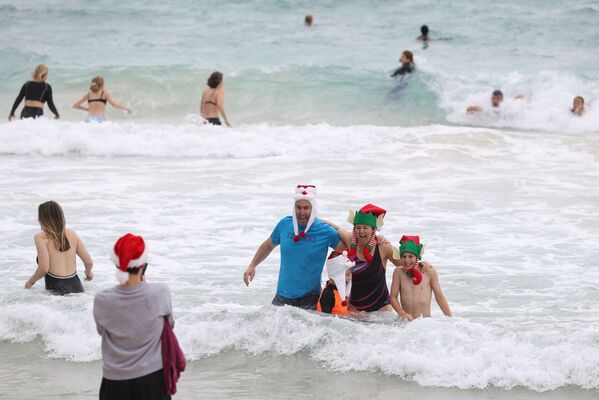 Люди в рождественской одежде позируют для фотографий в Рождество на пляже Бонди в Сиднее, Австралия - 俄罗斯卫星通讯社