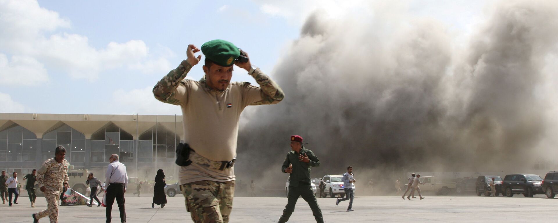 A security personnel member reacts as dust rises after explosions hit Aden airport, upon the arrival of the newly-formed Yemeni government in Aden, Yemen December 30, 2020. - 俄羅斯衛星通訊社, 1920, 13.06.2021