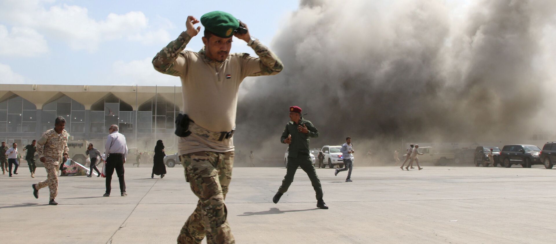 A security personnel member reacts as dust rises after explosions hit Aden airport, upon the arrival of the newly-formed Yemeni government in Aden, Yemen December 30, 2020. - 俄罗斯卫星通讯社, 1920, 30.12.2020