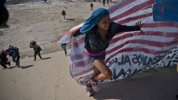 Женщина-мигрантка с флагом на границе США и Мексики - 俄罗斯卫星通讯社
