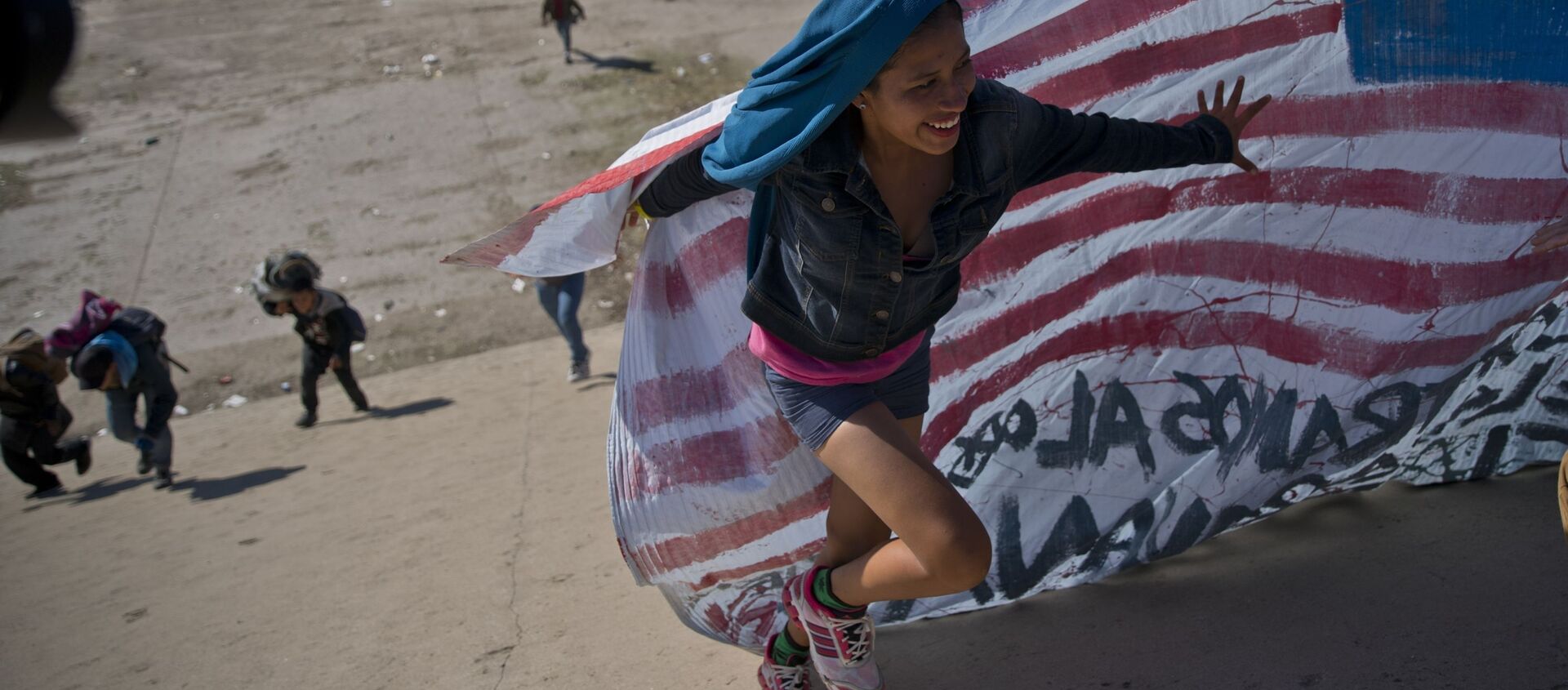 Женщина-мигрантка с флагом на границе США и Мексики - 俄羅斯衛星通訊社, 1920, 09.04.2021