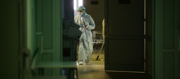 Медик в защитном противоэпидемическом костюме идет по коридору Новосибирской областной клинической больницы.  - 俄羅斯衛星通訊社