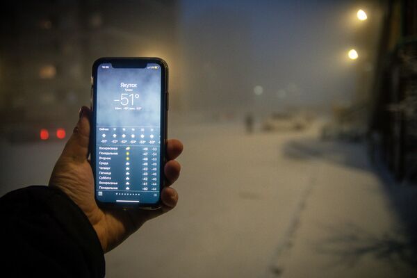 Мужчина демонстрирует мобильный телефон с информацией о прогнозе погоды в Якутске - 俄罗斯卫星通讯社