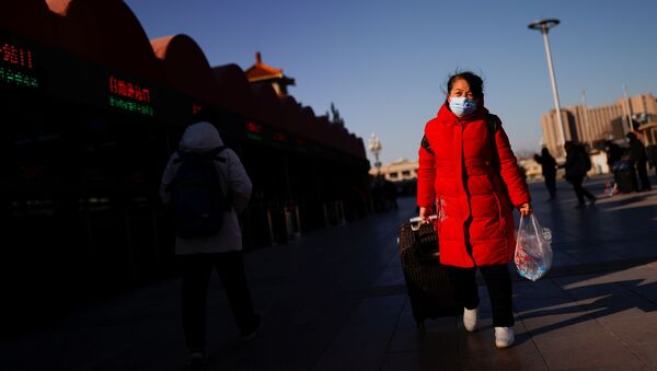 Путешественница в защтной маске у железнодорожного вокзала в Пекине, Китай - 俄罗斯卫星通讯社